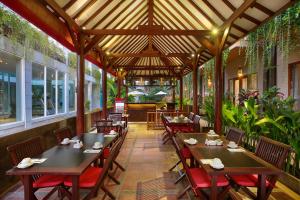 勒吉安巴厘岛勒吉安茶屋酒店的餐厅设有木桌和椅子,种有植物