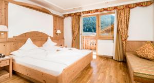 塞尔瓦迪加尔代纳山谷朵夫山魅力酒店的一间卧室设有一张大床和一个大窗户