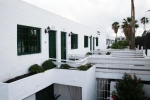 卡门港瓜纳拉玛公寓酒店的白色的建筑,设有绿色百叶窗和楼梯