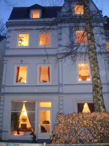 汉堡Alster City Garden Villa的白色的房子,窗户上有灯