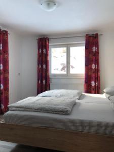 因斯布鲁克Apartment Gisi的一间卧室配有一张带红色窗帘的床和一扇窗户