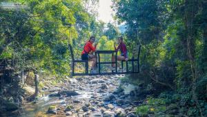 Ban Kat纳姆卡约拉霸度假村的两个女人坐在河上悬吊桥上
