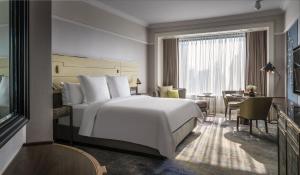 新加坡Four Seasons Hotel Singapore的酒店客房设有一张白色大床和一张书桌