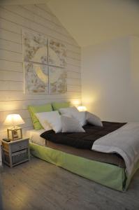 Beaumont-en-Auge普蒂特比尤蒙特酒店的一间卧室配有一张带绿色和白色枕头的大床