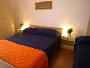 格拉多Condominio Alto Adriatico的一间卧室配有两张床和两个带灯光的床头柜。