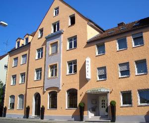 奥格斯堡法尔克奥格斯堡高德纳酒店的一座大型的橙色砖砌建筑,设有白色门