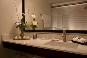 达拉姆达勒姆千禧国际酒店的浴室设有水槽、镜子和鲜花