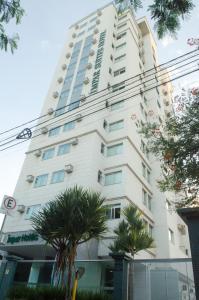 贝洛奥里藏特西达德新星伊姆帕尔套房酒店的一座高大的白色建筑,前面有棕榈树