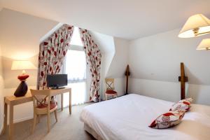 埃皮尼亚克Les Ormes Domaine et Resort的一间卧室配有一张床、一张书桌和一台电视。