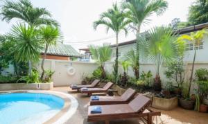 芭东海滩棕榈景度假酒店的一个带躺椅的度假村游泳池,并种植了棕榈树