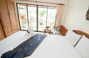 芭东海滩棕榈景度假酒店的一间卧室设有一张大床和一个大窗户