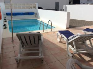普拉亚布兰卡Villa Anclazul Marina Rubicon的一个带两把椅子和一张床的游泳池