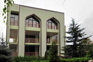 哈尔科夫Мини-Отель "Навруз"的公寓大楼设有2个阳台和1棵松树