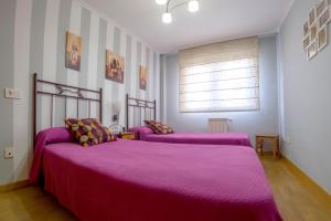 里瓦德塞利亚Apartamento Sella y Mar - VUT12AS的一间卧室配有两张紫色毯子的床
