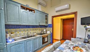 索伦托迪维纳住宿加早餐旅馆的厨房配有蓝色橱柜、水槽和桌子