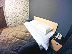 阿斯塔纳Mini-Hotel Pulsar的一间卧室,配有一张床,在床头柜上配有电话