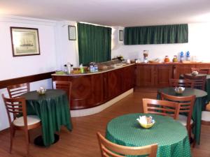 奇维塔韦基亚渡船酒店的带2张桌子的餐厅以及带绿色窗帘的厨房