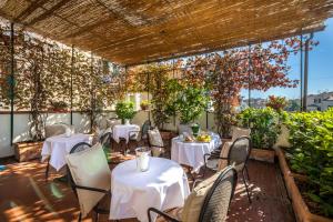 佛罗伦萨Hotel Emma Small Luxury Hotel的一间设有白色桌椅的餐厅,种植了植物