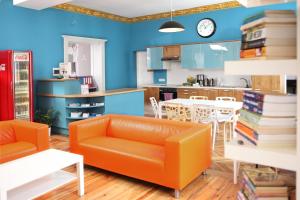 波兹南绽放精品旅馆的一间带橙色沙发的客厅和一间厨房