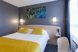 尼奥尔Kyriad Niort-Espace MendesFrance的酒店客房配有一张带黄色枕头的床