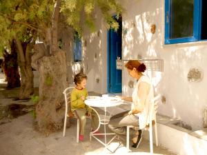 Livadi Astypalaias梅勒尼奥公寓酒店的坐在桌子上的妇女和儿童