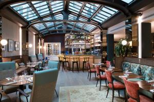 巴黎麦森博瑞固特酒店的餐厅设有桌椅和玻璃天花板