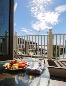 纽波特Almondy Inn Bed & Breakfast的阳台上的桌子上放有一盘水果和酒杯