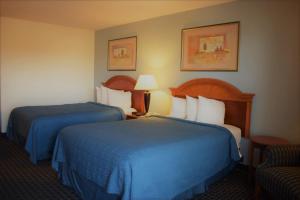 丹顿Texas Inn & Suites的酒店客房,配有两张床和椅子