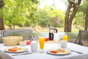 侯斯普瑞特Southern Sands Eco Lodge的餐桌,带食物盘和橙汁杯