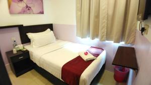 峇六拜Apple 1 Hotel Queensbay的一间酒店客房,配有一张带毛巾的床