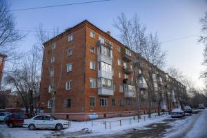 鄂木斯克Omsk Sutki Apartments on Ilyicheva 6的一座大型砖砌建筑,前面有汽车停放