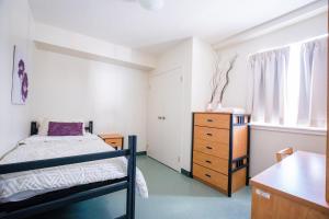 滑铁卢United College的一间卧室配有一张床和一个木制梳妆台
