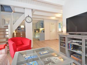 奥斯赛拜-塞林Blaues Strandhaus Sellin的一间带电视和红色椅子的客厅