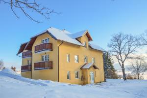兹拉蒂博尔Grand Hills Zlatibor的一座黄色的建筑,地面上积雪