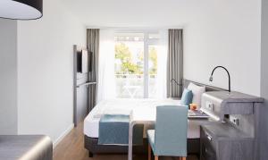 纽伦堡Living Hotel Nürnberg的一间卧室配有一张床、一张书桌和一个窗户。