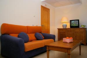 哈维亚巴伊亚皮诺索公寓式酒店的客厅里一张橙色的沙发,配有桌子