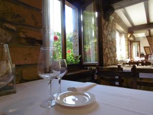 阿里纳斯·德·卡伯瑞勒斯Logis Hotel Restaurante La Casa de Juansabeli的餐厅的桌子上放着两杯酒