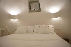 阿尔贝罗贝洛Trullo Essenza-Trulli Antì Charme & Relax的一张白色的床,墙上有两盏灯