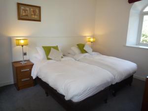 卡斯尔马特Castlemartyr Holiday Mews 2 bed的配有白色床单和绿色枕头的客房内的两张床