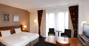 哈莱姆法兰斯哈尔斯阿姆拉斯大酒店的酒店客房配有一张床、一张书桌和一台电视。