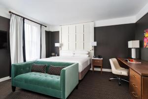 里士满The Commonwealth的酒店客房,设有一张床铺和一张绿色沙发