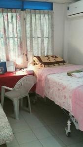 曼谷年轻美丽旅馆的一间卧室配有两张床、一张桌子和一把椅子