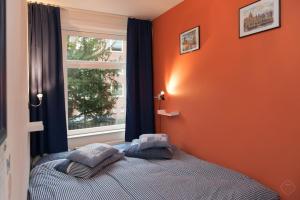 阿姆斯特丹B&B West City Amsterdam的一间卧室设有橙色墙壁和一张带两个枕头的床