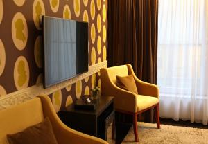 布鲁塞尔伊斯佩兰策酒店的一间房间,配有两把椅子和墙上的电视