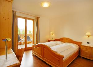 卡斯特尔罗托Urthalerhof的一间卧室设有一张大型木床和一个阳台。