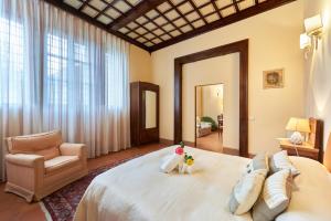 锡耶纳索奇尼别墅旅馆的卧室配有一张白色大床和一把椅子