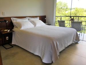 库尼亚Latitude Lodge的卧室配有白色的床和阳台