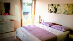 加利波利B&B Delfis的一间卧室配有一张带紫色枕头的床和窗户。