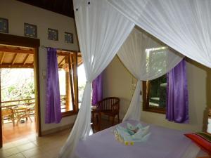 罗威那圣纳达洋房酒店的一间卧室配有一张带紫色窗帘的天蓬床