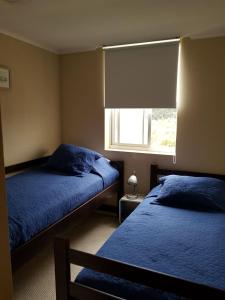 阿尔加罗沃Laguna Bahía, Algarrobo的一间卧室设有两张带蓝色床单的床和窗户。